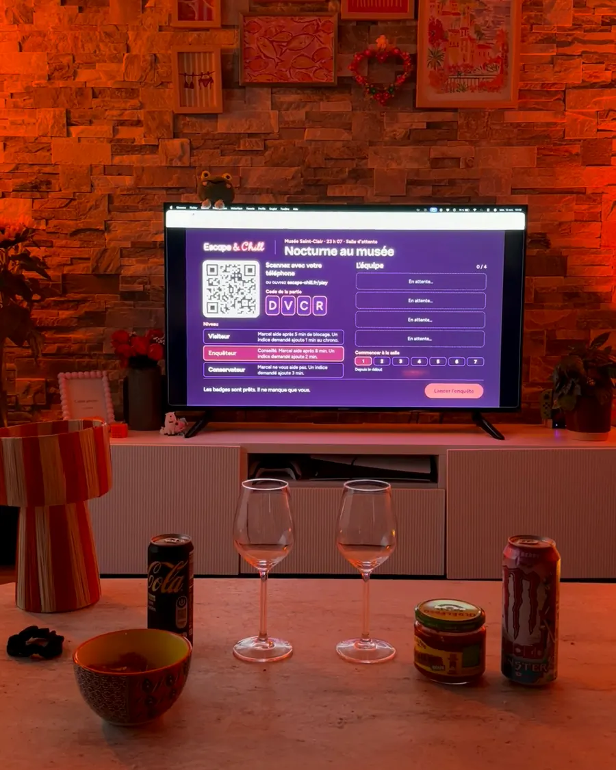Salon en lumière tamisée, la télé allumée devant une table basse avec des verres